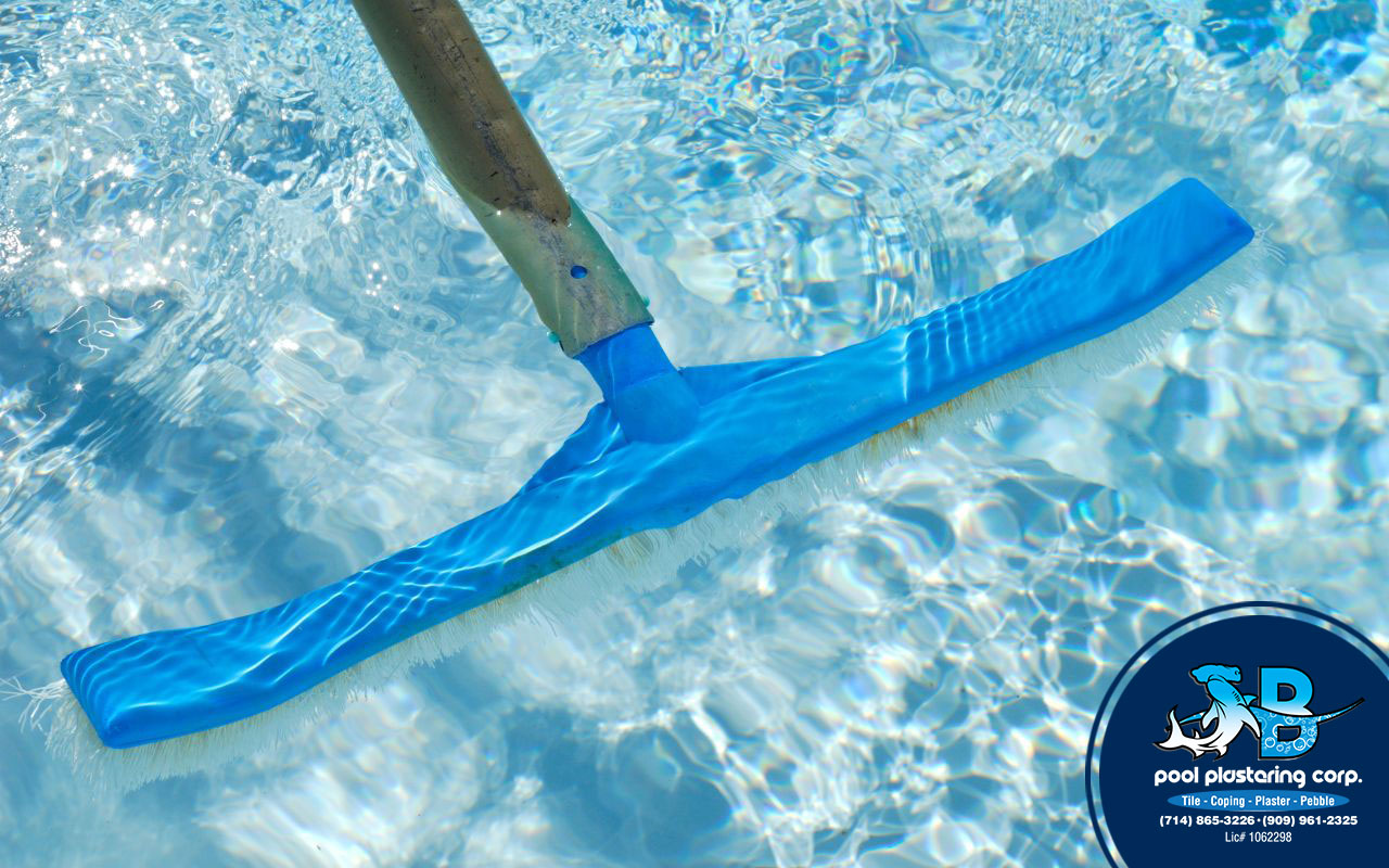 Brushing pool plaster to prevent algae and stains.